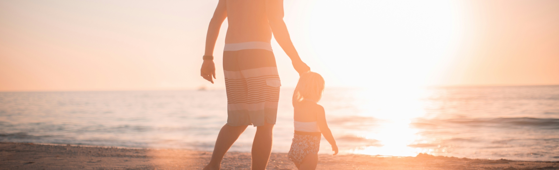 Father and son walking along the beach at sun set